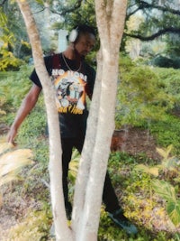 a man with headphones leaning against a tree